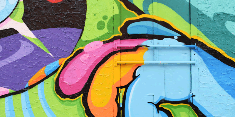 A vibrant graffiti mural featuring abstract shapes and bold colors, including green, blue, pink, purple, and yellow, painted on a textured wall with visible hinges, perfect for a social media planner | plannthat.com