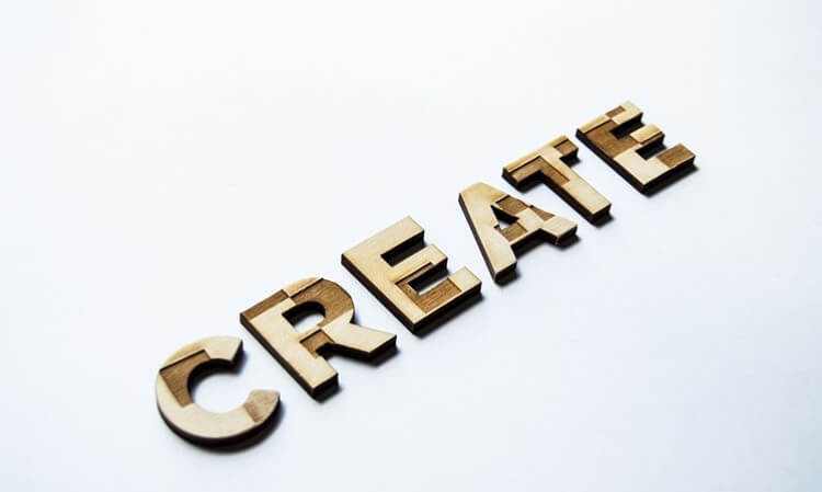 Wooden block letters spelling "CREATE" on a white background, with shadows adding depth and dimension | Social media planner | plannthat.com