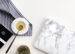 "A marble-patterned laptop, striped cloth, book, honey in a dish with spoon, and herbal tea on a white surface, creating a cozy workspace for using a social media scheduler" | plannthat.com