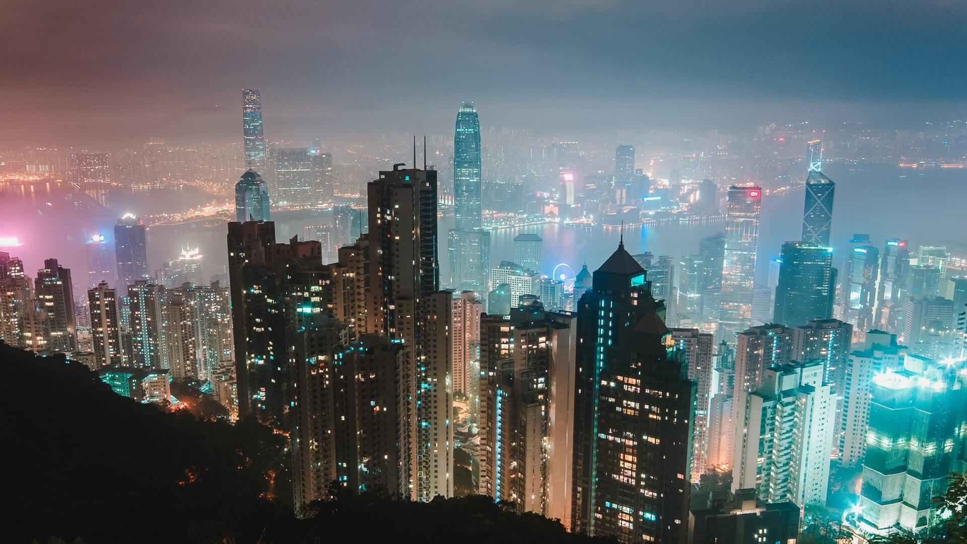 A vibrant cityscape at night with illuminated skyscrapers and a hazy sky, showcasing a bustling urban environment. The lights from the buildings create a colorful and dynamic atmosphere, highlighting the city's modern architecture and lively ambiance, perfect for a social media planner | plannthat.com