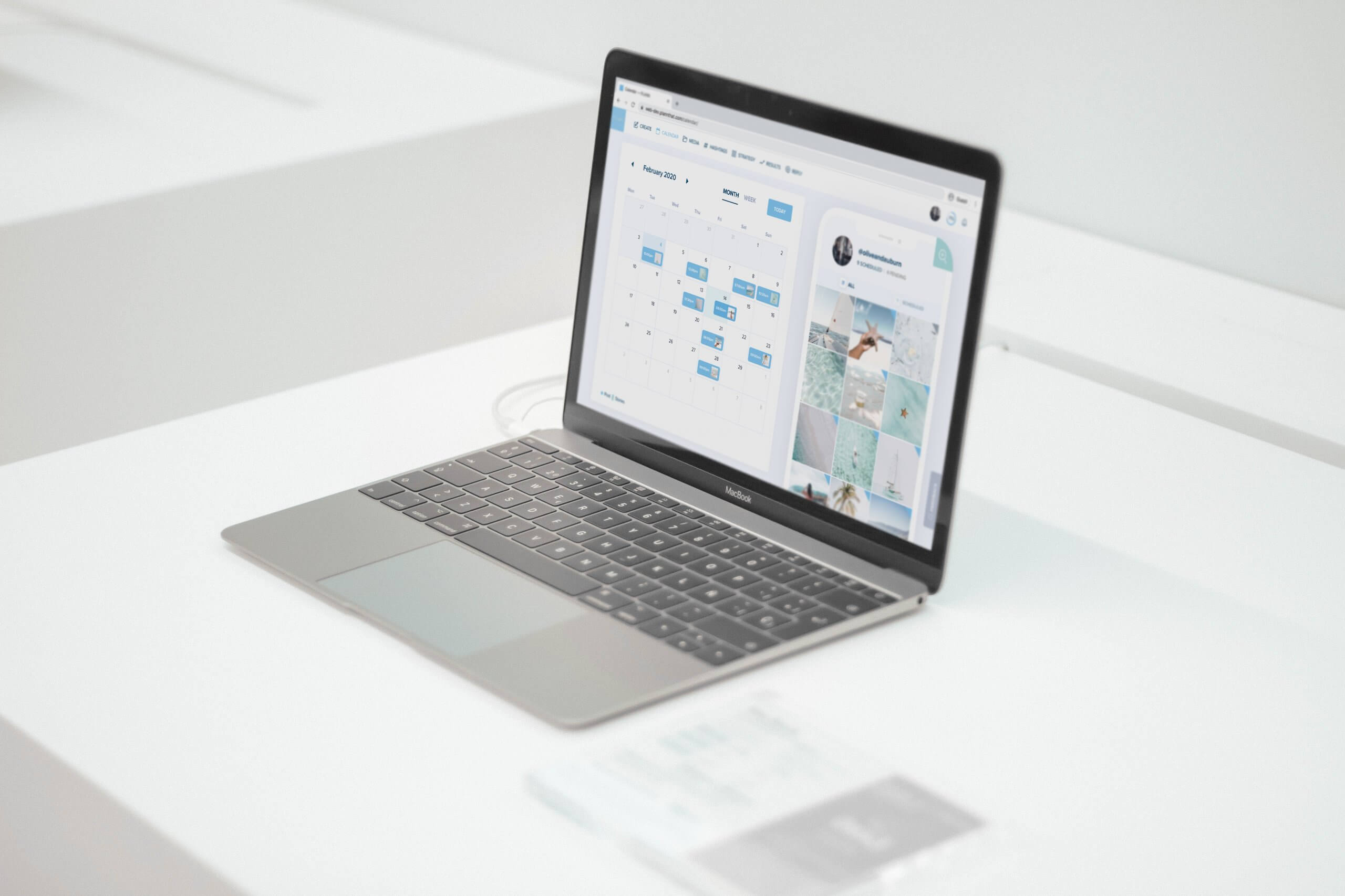 A sleek laptop displaying a calendar and social media planner tool on its screen, placed on a minimalist white desk in a clean and modern workspace setup | plannthat.com